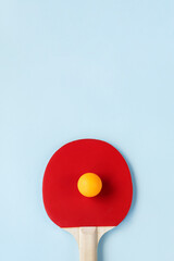 Ping pong paddle and ball on light blue background. Active lifestyle concept