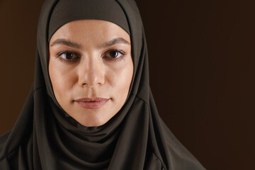 Naklejka premium Young muslim woman in hijab posing and looking at camera