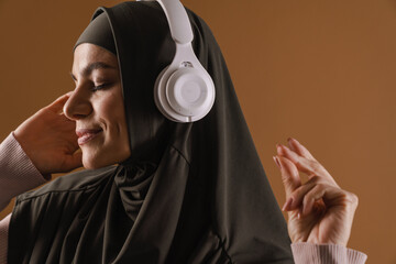 Young muslim woman in hijab listening music with headphones