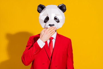 Photo of sorry guy palm cover mouth keep secret wear panda mask red suit isolated on yellow color...