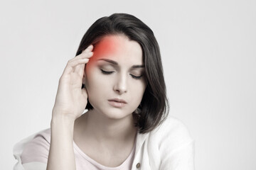 Fototapeta premium Tired sad brunette woman touches her head, migraine, pain area of red color. Headache concept.