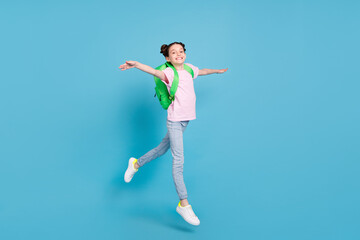 Fototapeta na wymiar Photo of cute adorable schoolgirl dressed pink t-shirt rucksack jumping high walking smiling isolated blue color background