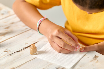 Girl painting her finger nails with nail varnish