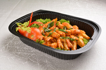 stir fried big tiger prawn with pumpkin creamy sauce and curry leaf in black party bento tray box for asian take away halal menu