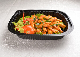 stir fried big tiger prawn with pumpkin creamy sauce and curry leaf in black party bento tray box for asian take away halal menu