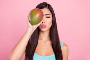 Photo portrait woman sending air kiss keeping exotic fruit covered face eye isolated pastel pink...
