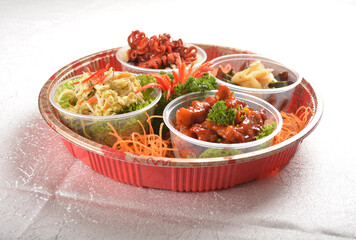 cold combo salad platter with sweet and sour pork, stir fried scrambler egg, preserved century egg with ginger and Japanese red marinated octopus in round party bento tray box for asian take away hala