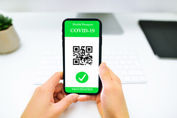 Young woman showing on her smartphone screen a certificate of immunity against Covid19. Concept of travel and health protocols during the corona virus pandemic.