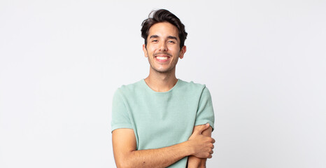 hispanic handsome man laughing shyly and cheerfully, with a friendly and positive but insecure...