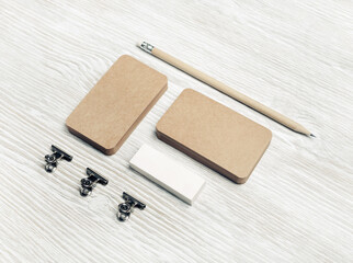 Blank kraft business cards, pencil and eraser on light wood table background. Branding mock up.