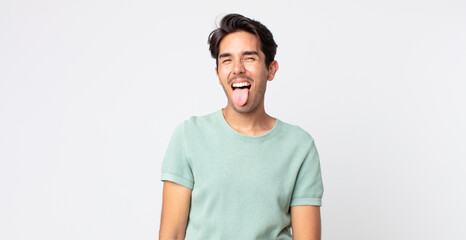 hispanic handsome man with cheerful, carefree, rebellious attitude, joking and sticking tongue out,...