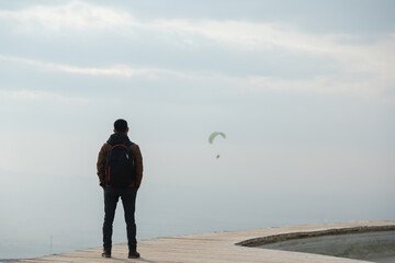 Man standing on mountain pathway and looking at the city