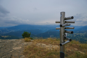 silver-colored metal signpost in the mountains close-up across aerial mountains view. Adventure, travel lifestyle. Pietra di Bismantova, Italy