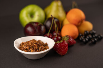 Fototapeta premium Fresh fruits and dried fruit powder. Pear, apple, apricot, cherry, currant, strawberry and plum on dark paper background. Vegetarian healthy detox food.
