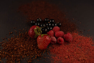 Fresh fruits and dried fruit powder. Cherry, currant, strawberry and raspberries  on dark paper...