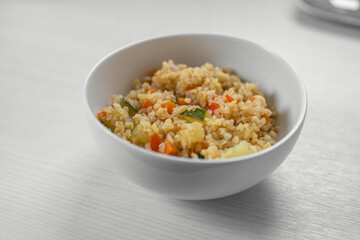 Bulgur with vegetables in the bowl on the white wooden table. Concept of Healthy Food. Healthy diet concept. Super Food. Vegetarian.