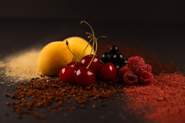 Fresh fruits and dried fruit powder. Apricot, cherry, currant and raspberries  on dark paper background. Vegetarian healthy detox food.