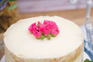 White wedding cake decorated by flowers standing of festive table. Copy, empty space for text