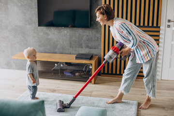 Young mother with toddler son cleaning up at home