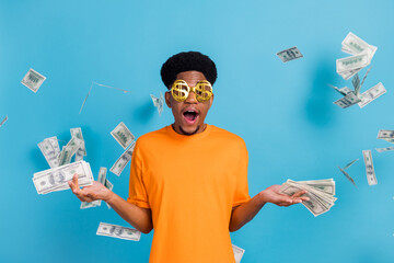 Portrait of attractive cheerful cool guy throwing cash flow usd deposit isolated over bright blue color background