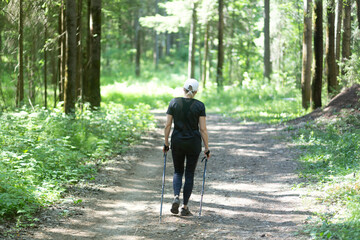 A woman is engaged in Nordic walking in the park. Outdoor fitness.