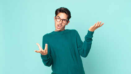 hispanic handsome man shrugging with a dumb, crazy, confused, puzzled expression, feeling annoyed...