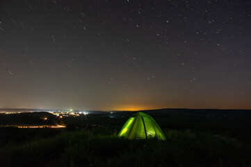 Night landscape tent against the background of the starry sky and city lights