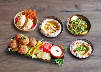 Fototapeta na wymiar Five plates and bowls with mezze appetizer on wooden background