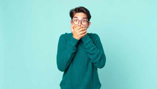 hispanic handsome man covering mouth with hands with a shocked, surprised expression, keeping a secret or saying oops