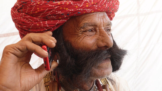 Elderly Indian man in traditional clothes and turban talking on the phone