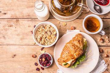 Healthy breakfast concept. Morning good mood with tea, croissant, granola, milk, and jam