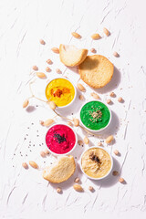 Various hummus dips, the flat lay of hummus in different colors with spinach, beetroot, turmeric and vegetables