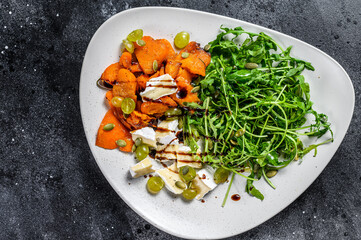 Grilled pumpking warm salad with arugula, walnuts and brie cheese. Black background. Top view