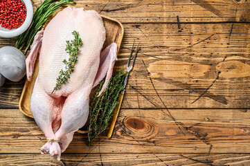 Raw whole farm duck with herbs. wooden background. Top view. Space for text