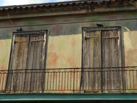 Wooden doors at the second floor of an old building, with birds perched on the door tops