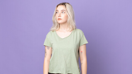 pretty albino woman with a worried, confused, clueless expression, looking up to copy space,...