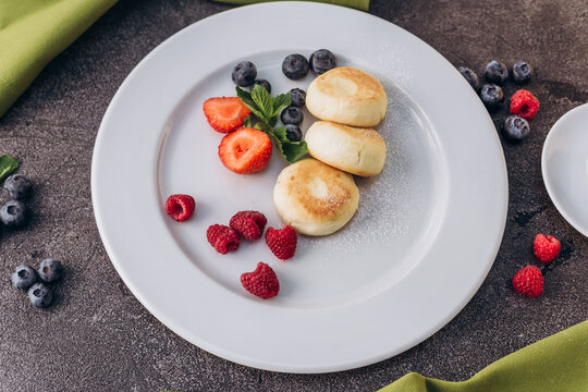 Nutritious vegetarian breakfast with cheesecakes and berries. 