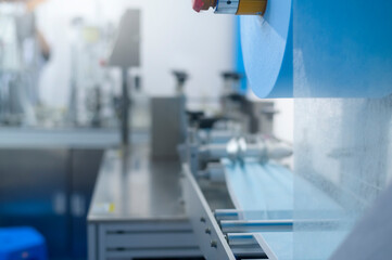 Close up of machine producing surgical mask in modern factory, Covid-19 protection and medical concept.