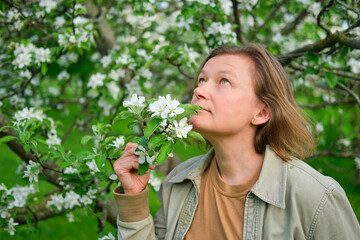 Adult woman in the spring park near the spring apple trees, portrait