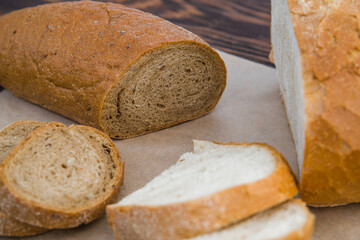 delicious white wheat and rye bread on parchment and a wooden table. the concept of gluten-free and food products, baking
