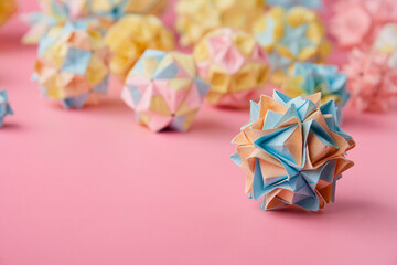 Set of multicolor handmade modular origami balls or Kusudama Isolated on pink background. Visual...