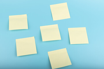 yellow sticky notes on blue background. Square sticky paper reminders with shadows