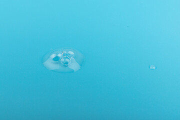 face serum drop in close up on blue background.