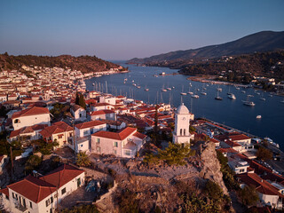 Drone view of Poros island. Clock tower in old town with traditional white houses near the sea. Saronic gulf, Greece, Europe.