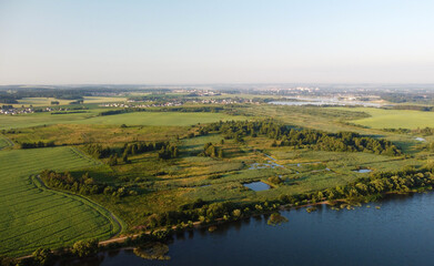 Fototapeta na wymiar Aerial view of green shore of blue lake on summer morning