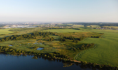 Fototapeta na wymiar Aerial view of green shore of blue lake on summer morning
