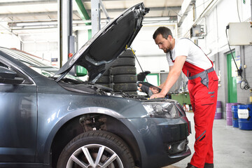 Fototapeta na wymiar car mechanic in work clothes checks engine from a car in a workshop