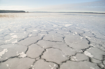 Fototapeta na wymiar Frozen Lake Usma with cracked ice. Sunny winter day without snow. 