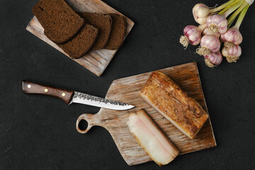 Overhead view of smoked lard with brown bread on wooden cutting board