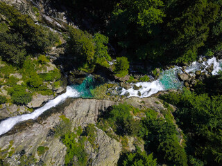 Aerial drone view of a waterfall in a river with turquoise water located in a green natural environment in Pyrenees, Spain.